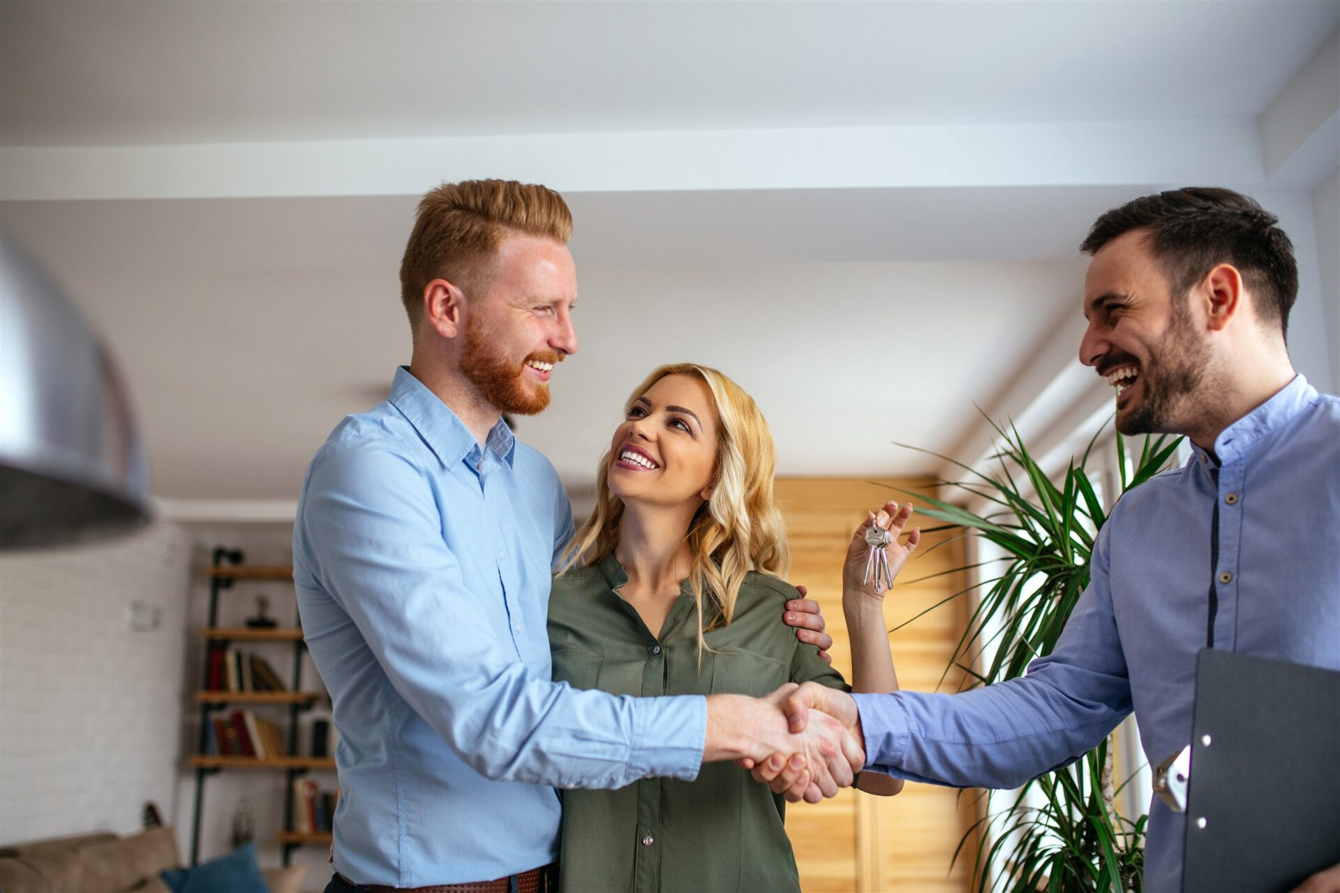 Estate agent handing keys to smiling home buyers