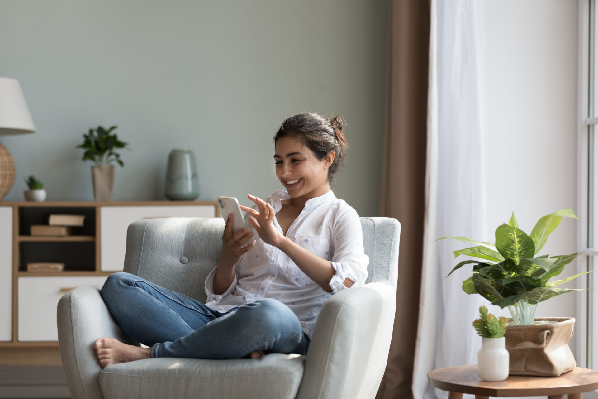 Woman using a smartphone while relaxing at home in Trowbridge