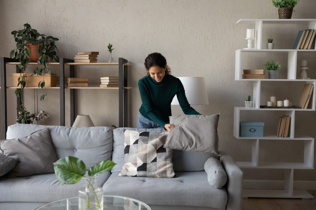 Woman arranging cushions on a sofa.