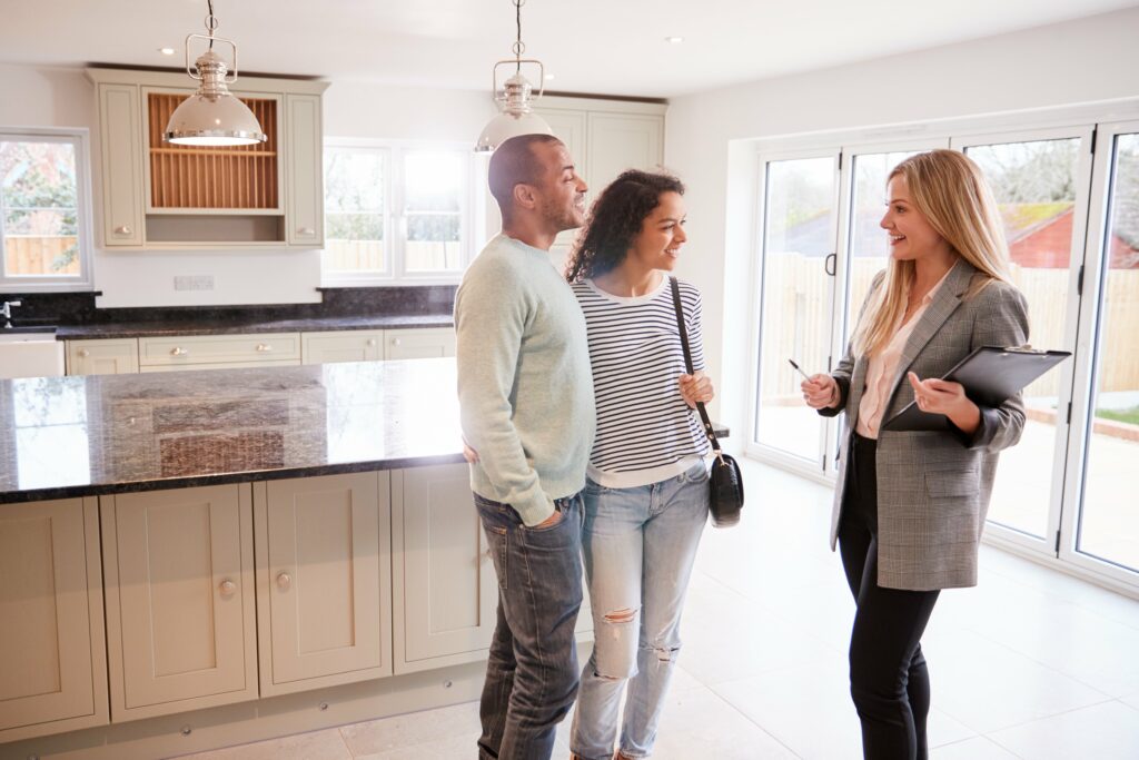 female real estate agent showing couple around a house